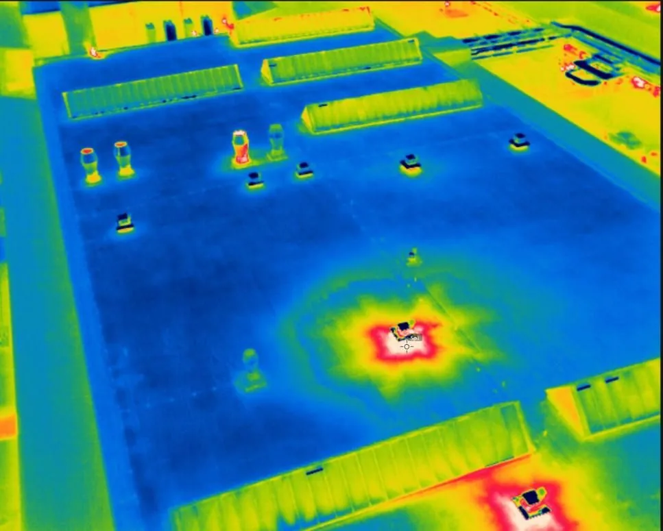 Aerial thermal image of an industrial roof showing a clear hot spot against cooler surroundings